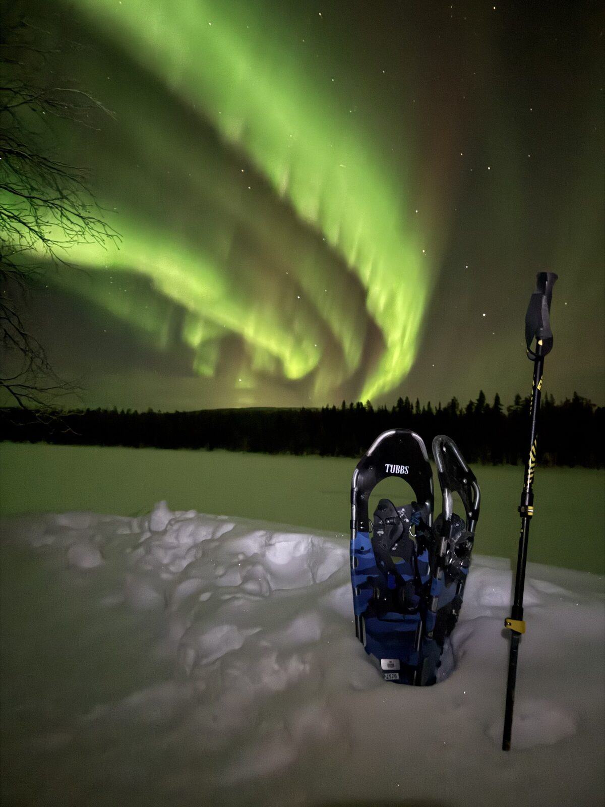 Schneeschuhe im Schnee, Nordlicht über einem See